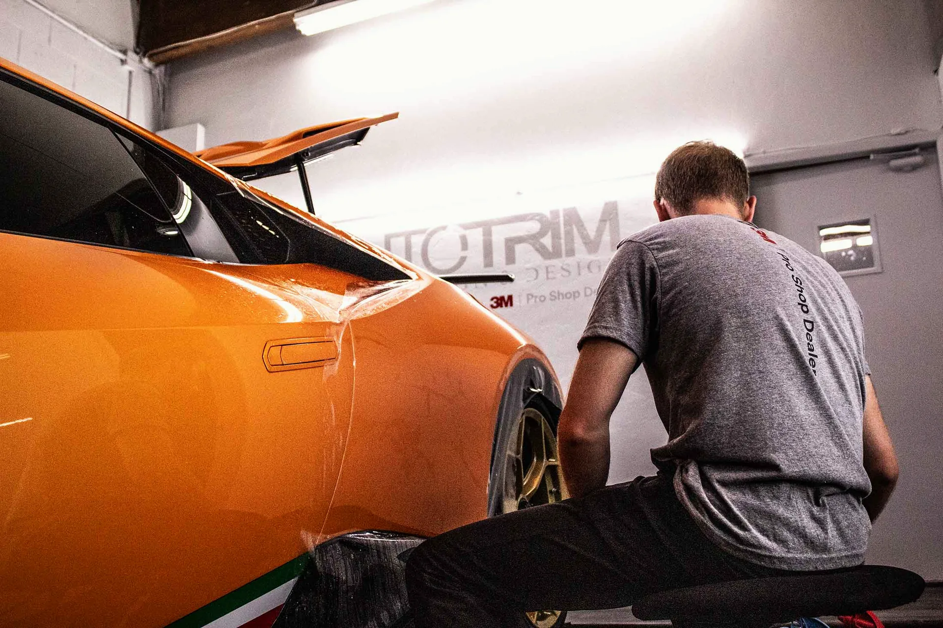 Paint protection film being applied to an orange Lamborghini