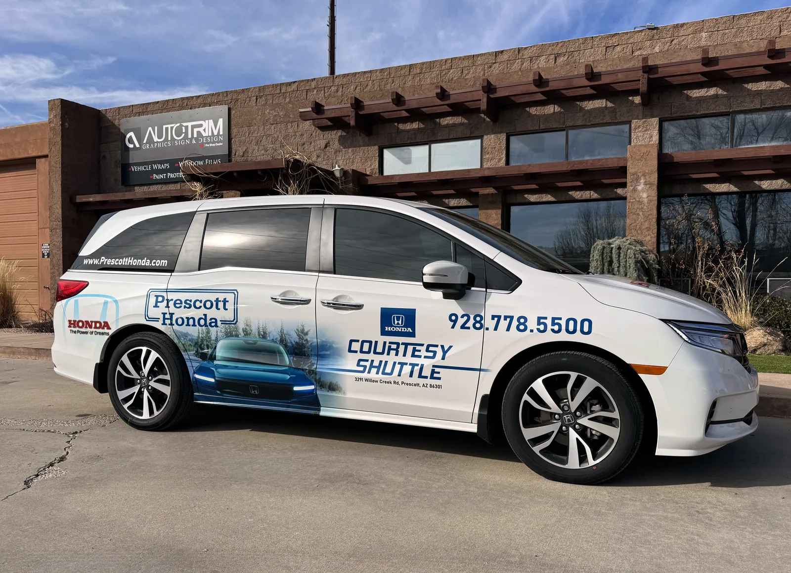 A Prescott Honda courtesy shuttle in a partial wrap outside the Auto Trim Plus shop