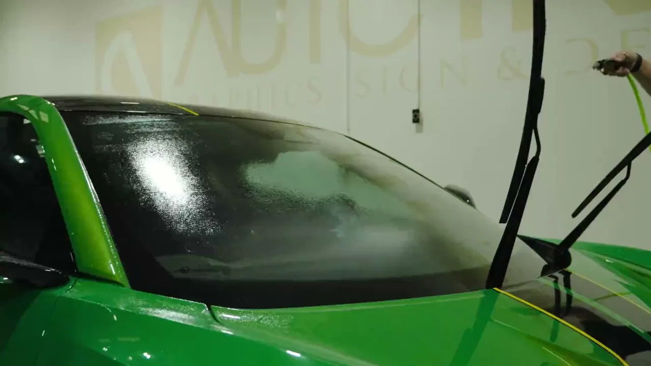 Clear protection film being laid onto a vehicle windshield