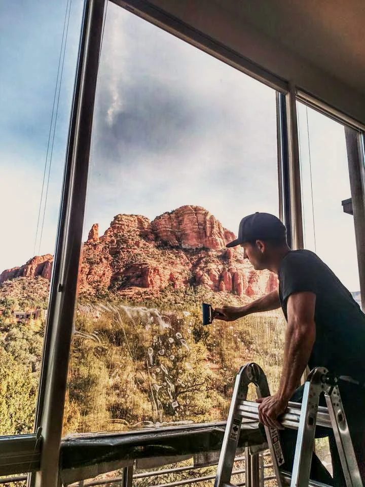 Installer applying 3M window film to a picture window overlooking red rock country